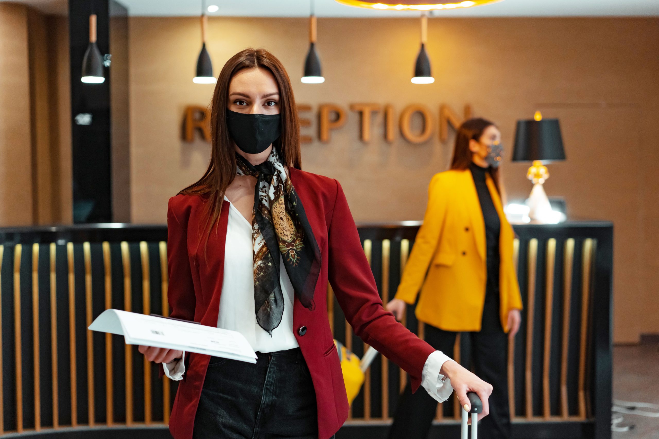 Réceptionniste masquée à cause de la crise sanitaire qui accompagne une cliente d'hôtels-restaurants